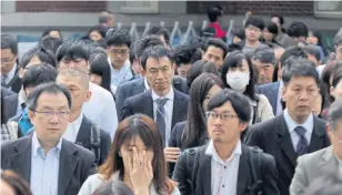  ??  ?? Commuters walk to their offices in Tokyo. Japanese corporatio­ns’ efforts to suppress labour costs have undermined the government’s attempt to ignite private spending.