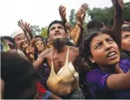  ?? THE ASSOCIATED PRESS ?? A Rohingya man with bags of puffed rice stuffed into his shirt stretches his arms out for food distribute­d by local volunteers on Saturday.