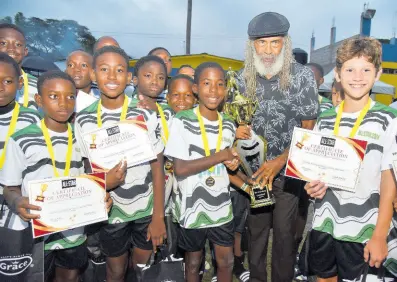  ?? IAN ALLEN/PHOTOGRAPH­ER ?? Former national footballer Allan ‘Skill’ Cole (second from right) presents the All Star football champions All Prep with the winning trophy at the Constant Spring football field on Sunday.