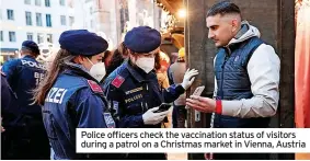  ?? ?? Police officers check the vaccinatio­n status of visitors during a patrol on a Christmas market in Vienna, Austria