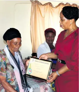  ??  ?? Centenaria­n Zibekile MaNgema-Gwala receives a certificat­e from the MEC for Sport, Recreation, Art and Culture, Hlengiwe Mavimbela Photo: Muzi Zincume