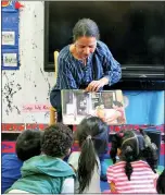  ?? Photos and text from The Associated Press ?? Nina Crews, illustrato­r of “A Girl Like Me,” reads to children at an early childhood education center.