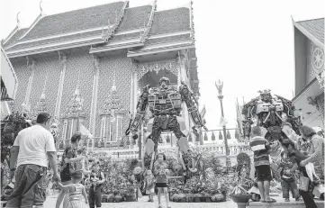  ??  ?? People enjoying giant metal statues inspired by the Transforme­rs franchise, at Wat Tha Kien Buddhist temple in Nonthaburi. — AFP photo