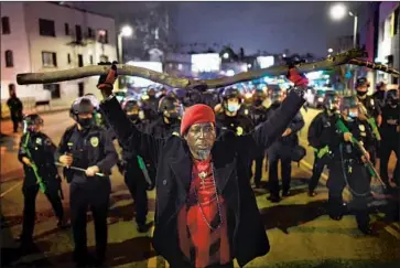  ?? Los Angeles Times ?? A PROTESTER is pushed back by police as authoritie­s clear out an Echo Park Lake camp on March 25.