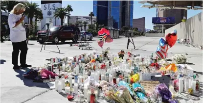  ?? | CHRIS CARLSON/ AP ?? Awoman looks over a makeshift memorial on Las Vegas Boulevard on Tuesday in Las Vegas.