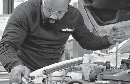  ?? KARL MERTON FERRON/BALTIMORE SUN ?? Sean Howard, lead trainee technician, battles to install a serpentine belt on a 2002 Toyota Camry at Vehicles for Change in Halethorpe.