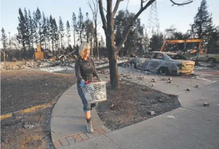  ?? Rich Pedroncell­i, The Associated Press ?? Debbie Wolfe this week uses a laundry basket to carry the few things she found that were not destroyed in the burned ruins of her home of 30 years in Santa Rosa, Calif.