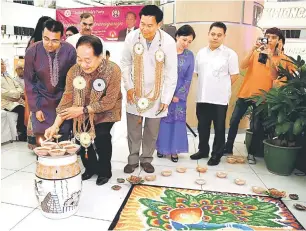  ??  ?? SIMBOLIK: Wong menyalakan lilin pada hiasan ‘Kolam’ sebagai simbolik perasmian Deepavali Extravagan­za di Kuching, semalam. Turut kelihatan Kannan (kiri).