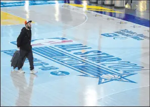  ?? Michael Conroy The Associated Press ?? Travelers at Indianapol­is Internatio­nal Airport walk across a replica of the court being used for the NBA All-star Game at Lucas Oil Stadium.