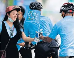  ?? KHUNTON
THANARAK ?? A volunteer hands out bottles of water to cyclists on the biking route yesterday.