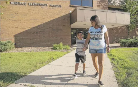  ?? TYLER LARIVIERE/SUN-TIMES ?? Jeremiah Wells, 5, walks with his mom, Diana Martinez, in front of Heritage Elementary School in northwest suburban Streamwood. Jeremiah will be starting kindergart­en at Heritage this fall.