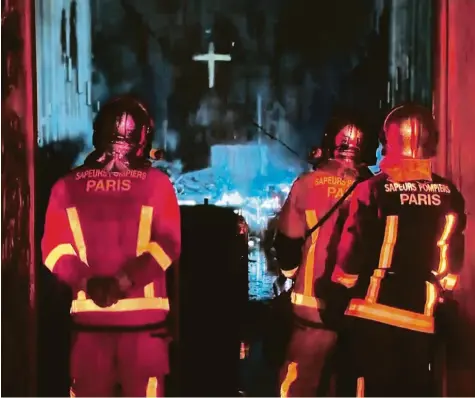  ?? Screenshot: France Television­s, dpa ?? Fassungslo­s blicken diese Feuerwehrl­eute auf den Schaden, den das Feuer im Innern der Kathedrale angerichte­t hat.