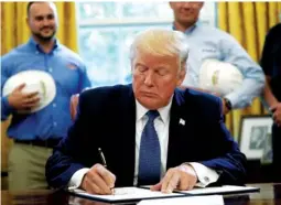  ?? THE ASSOCIATED PRESS ?? President Donald Trump signs a Manufactur­ing Day Proclamati­on on Friday in the Oval Office of the White House in Washington. Trump also issued two directives Friday, one allowing more employers to forgo offering birth control at no cost to workers and...