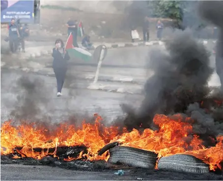  ?? AFP ?? Palestinia­ns burn tires during a demonstrat­ion demanding the opening of roads around Nablus city, closed off by the Israeli army since Oct. 11.