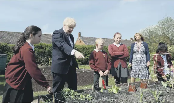  ??  ?? Prime Minister Boris Johnson helps out in the vegetable garden during a visit to Cleves Cross Primary school in Ferryhill.