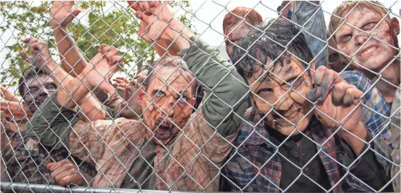  ?? VALERIE MACON, AFP/GETTY IMAGES ?? Zombie characters push on a fence at Universal Studios Hollywood’s opening of The Walking Dead attraction in Universal City.