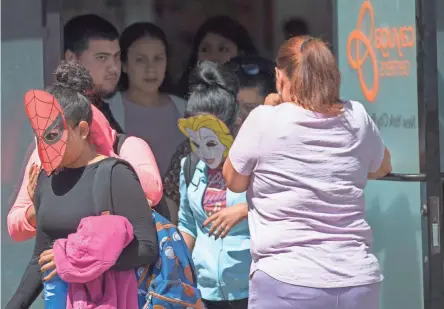  ??  ?? Children are escorted from the Cayuga Centers facility Thursday in New York. Many wore homemade masks that made it impossible to tell which had been removed from their parents by federal officials.
