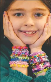  ??  ?? Hayley poses for a portrait with several colorful rubber band bracelets she makes in her Chicago home.