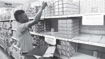  ??  ?? A worker removing corned beef from the shelves at a Sampars store in Kingston yesterday.