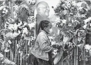  ?? Nardus Engelbrech­t / Associated Press ?? A mourner places a floral tribute Tuesday outside St. George's Cathedral in Cape Town, South Africa. The funeral for Desmond Tutu, who died Sunday at the age of 90, will be New Year's Day.