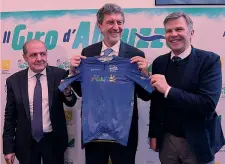  ?? LAPRESSE ?? Maglia azzurra Da sinistra Mauro Vegni, direttore area ciclismo Rcs Sport; Marco Marsilio, presidente della Regione Abruzzo con la maglia azzurra del leader del Giro; Paolo Bellino, a.d. di Rcs Sport