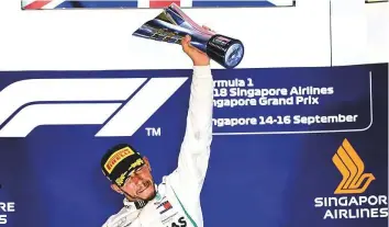  ?? AFP ?? Mercedes’ Lewis Hamilton holds up the trophy on the podium after winning the Singapore Grand Prix at the Marina Bay Street Circuit yesterday.