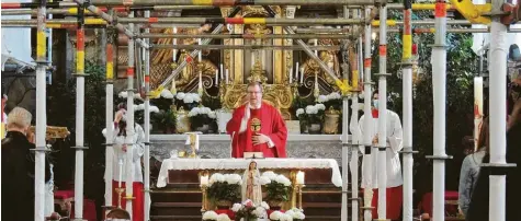  ?? Fotos: Winfried Rein ?? Eingerahmt von Gerüsten spendet Pfarrer Herbert Kohler den Pfingstseg­en in der Heiliggeis­t-Kirche. Die Sanierung des Gotteshaus­es geht deutlich voran.