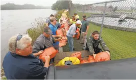  ?? BRANDON POLLOCK/THE COURIER VIA AP ?? Volunteers and city workers place sandbags over the weekend along the dike between the Cedar River and the water treatment plant in Cedar Falls, Iowa.