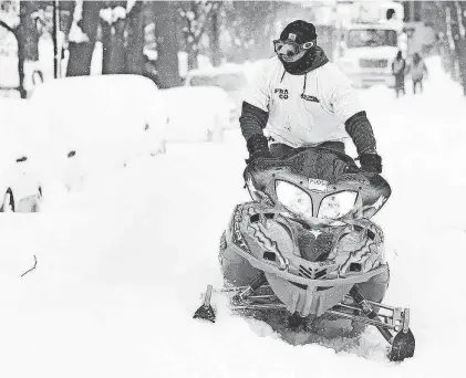  ?? JOSEPH COOKE/BUFFALO NEWS ?? Alex King rides a snowmobile through a neighborho­od in Buffalo's Elmwood Village on Dec. 26, 2022, as the Christmas weekend blizzard waned. Most snowmobile­rs who helped stranded motorists and those in need of other help during the blizzard did so informally.