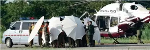  ?? AFP ?? Police and military personnel use umbrellas to cover around a stretcher at a military airport in Chiang Rai on Monday, as rescue operations continue for those still trapped inside the cave. —