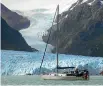  ??  ?? Alan Forrest and his partner Anne Pilcher Gough sailing past a glacier in South America during their world trip.