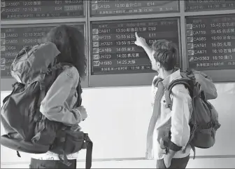  ?? PROVIDED TO CHINA DAILY ?? Two travelers check a flight informatio­n display at a Chinese airport.