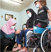  ??  ?? A helping hand: Nur aleesya massaging siti Khadijah’s leg at her flat in Taman Cendana, pasir Gudang. looking on is siti Khadijah’s grandson Muhd habibullah.