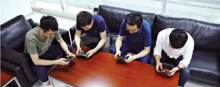  ??  ?? Game players try out 360 Technology’s e-sports smartphone at its release event. E-sports have entered the scene of diversifie­d games, including mobile titles, powerful smartphone­s, online broadcasti­ng platforms and emerging profession­al event organizers.