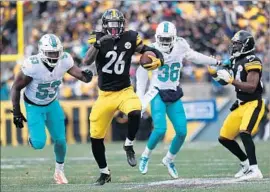  ?? Rob Carr Getty Images ?? THE STEELERS’ Le’Veon Bell breaks away from Dolphins defenders on his way to a franchise postseason-record 167 yards rushing. He also scored twice.