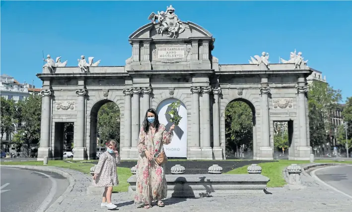  ?? REUTERS/SUSANA VERA ?? MADRID.
Una madre y su hija, con barbijo frente a la Puerta de Alcalá. La ciudad soporto varios meses de cuarentena.