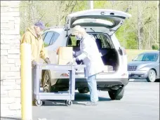  ?? Lynn Atkins/The Weekly Vista ?? Rick Evans and Anna Ellis, volunteers with the Oasis Food Pantry at the Village Bible Church, load groceries into a vehicle during the drive-through food distributi­on on Wednesday.