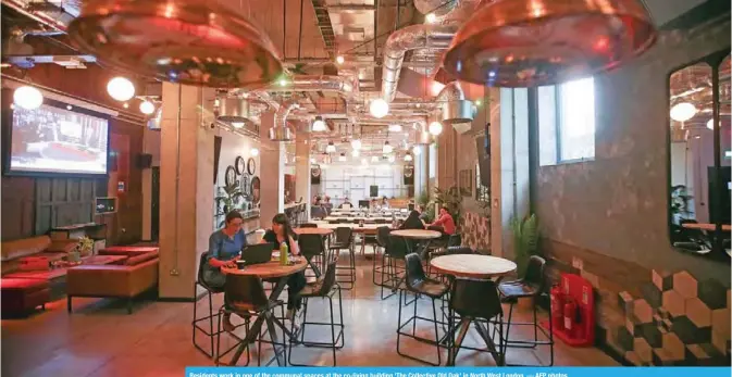  ?? — AFP photos ?? Residents work in one of the communal spaces at the co-living building ‘The Collective Old Oak’ in North West London.