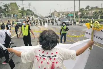  ?? Josie Norris Los Angeles Times ?? BRENDA BARAQUIL stands before L.A. County sheriff ’s deputies wearing riot gear earlier this month during a protest seeking justice for Dijon Kizzee, who was killed by deputies Aug. 31 in Westmont.