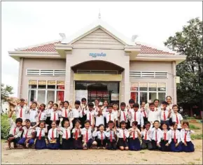  ?? SUPPLIED ?? Excited students at remote school wave to the camera in front of a modern library built by ChildFund Cambodia.