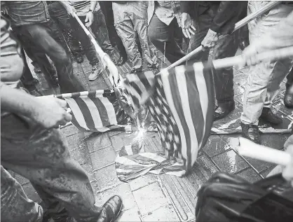  ?? VAHID SALEMI THE ASSOCIATED PRESS ?? Iranian demonstrat­ors burn representa­tions of the U.S. flag during a protest in front of the former U.S. Embassy in Tehran in response to President Donald Trump's decision last week to pull out of a nuclear deal and renew sanctions.