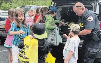  ?? JULIA LLOYD/SPECIAL TO THE EXAMINER ?? Students from North Shore Public School grab food donations from Hiawatha Police Const. Terry Rose’s cruiser for the 4th annual Cram-A-Cruiser food drive at Keene United Church on Wednesday.