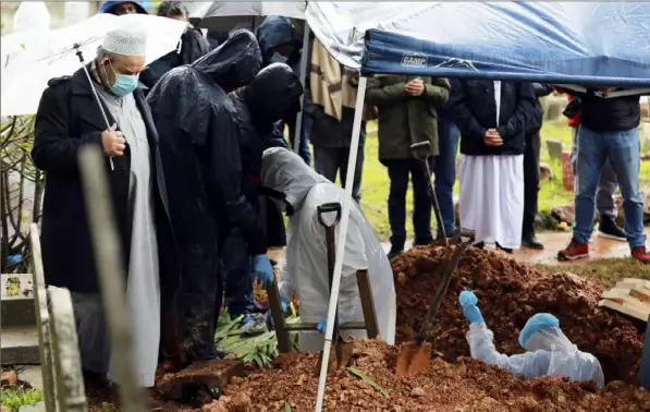  ?? Nardus Engelbrech­t/Associated Press ?? Undertaker­s wearing personal protective equipment exit the grave of Sheikh Seraj Hassan Hendricks during the funeral Friday at the Mowbray cemetery in Cape Town, South Africa. Sheikh Hendricks, who died of COVID-19, was the resident sheikh at the Azzawia Institute.