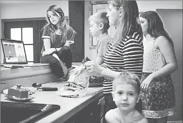  ??  ?? Annie Cole (left) shows her family a YouTube video. The Coles don’t have cable; all of their children prefer to watch YouTube, which has become the world’s largest platform for children’s entertainm­ent.— The Washington Post photo by Erin Hull