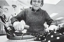  ?? AP ?? Judy Anderson irons a dress at the Sewing Basket in Montpelier, Vt. Despite falling out of favor in Monopoly, irons are still popular.