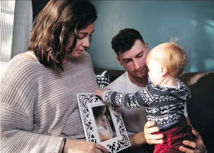  ?? ALLEN McINNIS ?? Hannah Aubut and her husband Scott with their child Cyan on Friday. Hannah holds a photo of her deceased child, Senna.