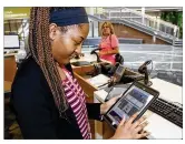  ?? TY GREENLEES / STAFF ?? Dayton Metro Library services assistant Destinee Hamilton sets up an e-book reader for a patron at the main library on East Fifth Street in Dayton.