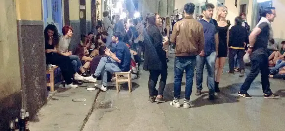  ??  ?? Folla in mezzo di strada (e marciapied­i come tavolini) sabato sera in Borgo La Croce A destra i cartelli anti bivacchi su un portone