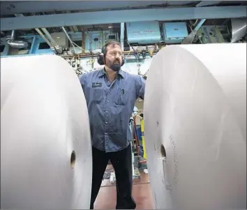  ?? Photograph­s by Natalie Behring Getty Images ?? JASON CAMPBELL adjusts rolls of newsprint at the Columbian in Vancouver, Wash., last month. The U.S. has levied two sets of duties on producers and exporters of uncoated groundwood paper from Canada.