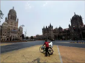  ?? REUTERS ?? ANOTHER LOCKDOWN: A man walks with his bicycle in front of the Brihanmumb­ai Municipal Corporatio­n building and the Chhatrapat­i Shivaji Maharaj Terminus (CSMT) during a weekend lockdown to limit the spread of COVID-19 in Mumbai on Saturday.
